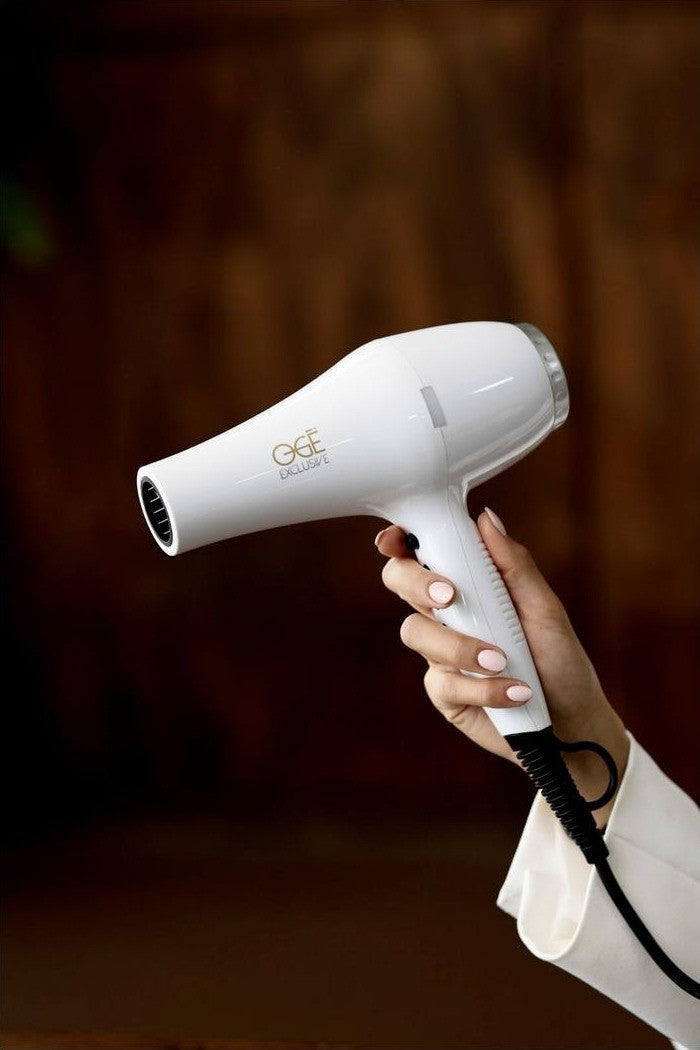 Ionische Haardroger, wit, in de hand gehouden tegen een warme houten achtergrond